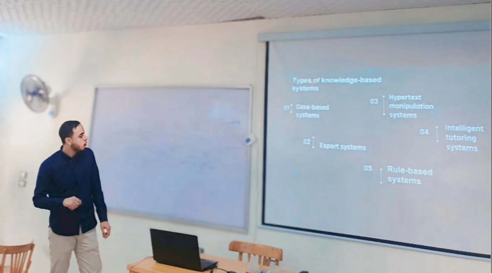The tutor presenting in a classroom setting, with a projected slide behind him.
