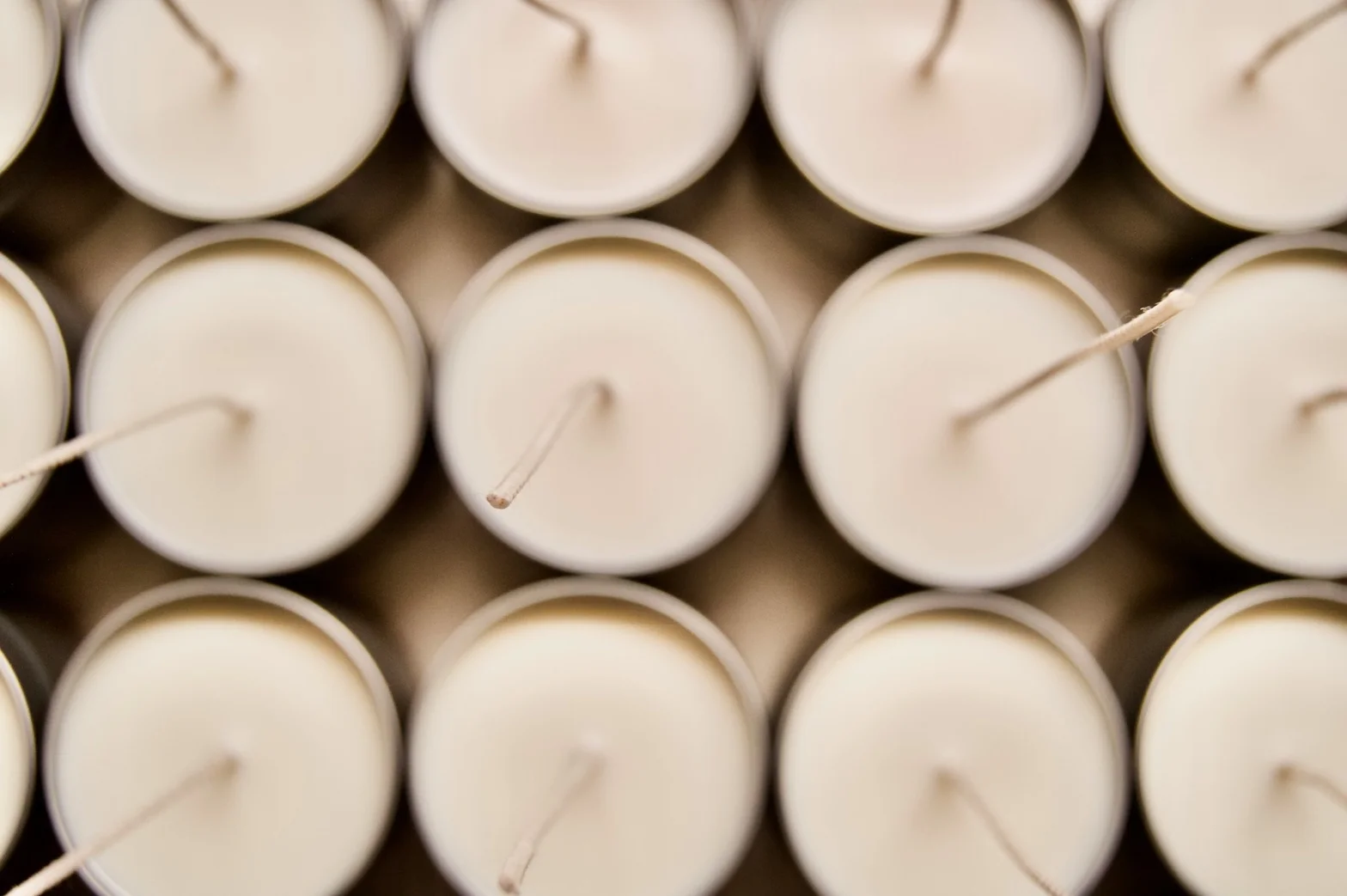 Overhead view of white candle rows with cotton wicks arranged in a grid