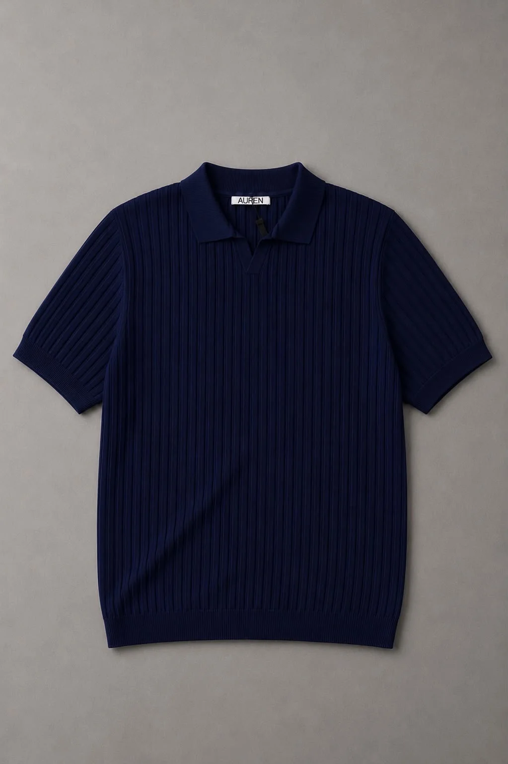 Polo de malha azul-marinho com textura plissada vertical, gola clássica e mangas curtas, fotografado sobre um fundo neutro.
