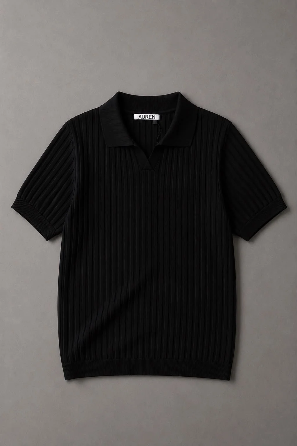 Camisa polo preta de manga curta, com textura plissada vertical, gola clássica e acabamento canelado na barra e nas mangas.