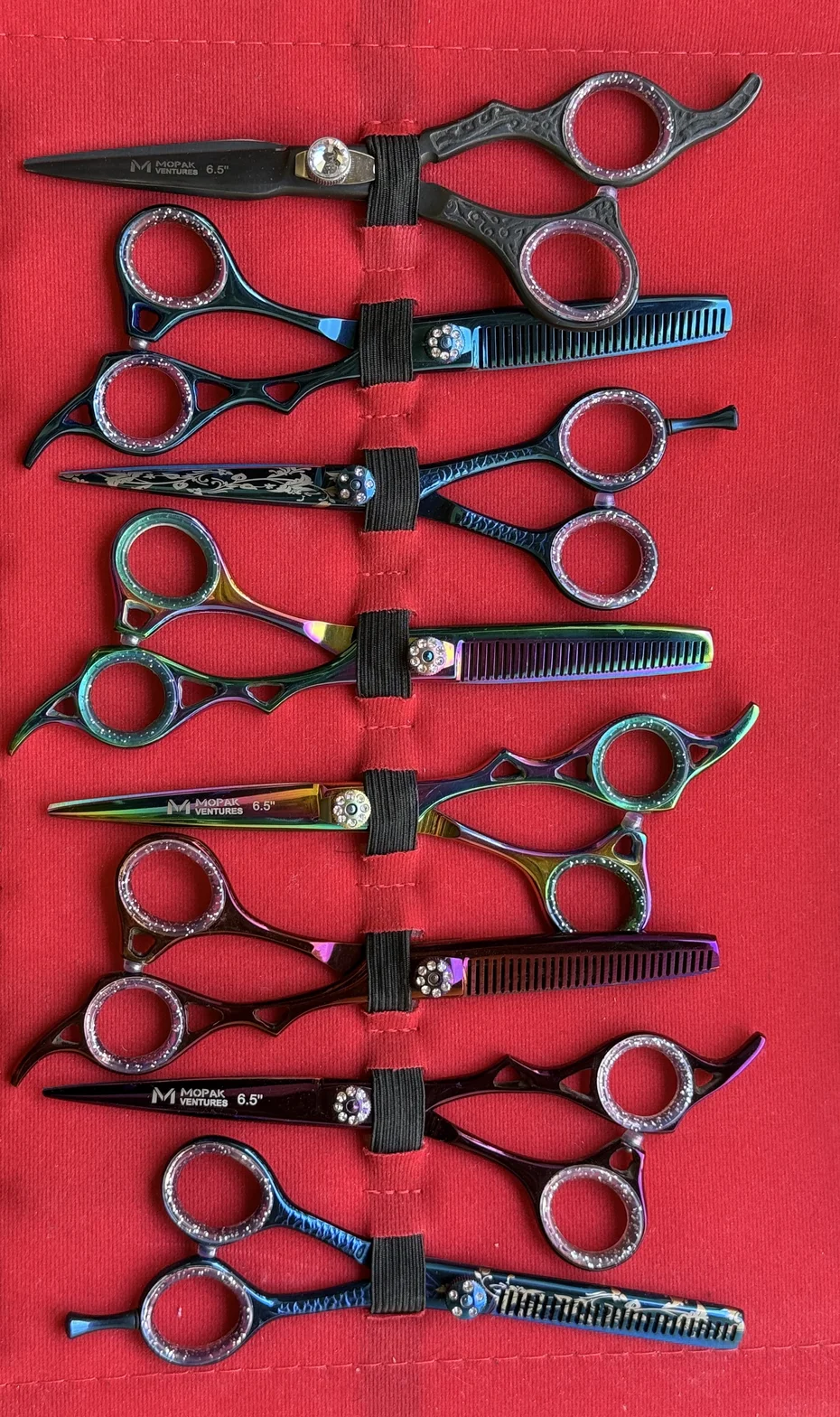 Colorful professional hair-cutting scissors and thinning shears arranged on a red fabric display