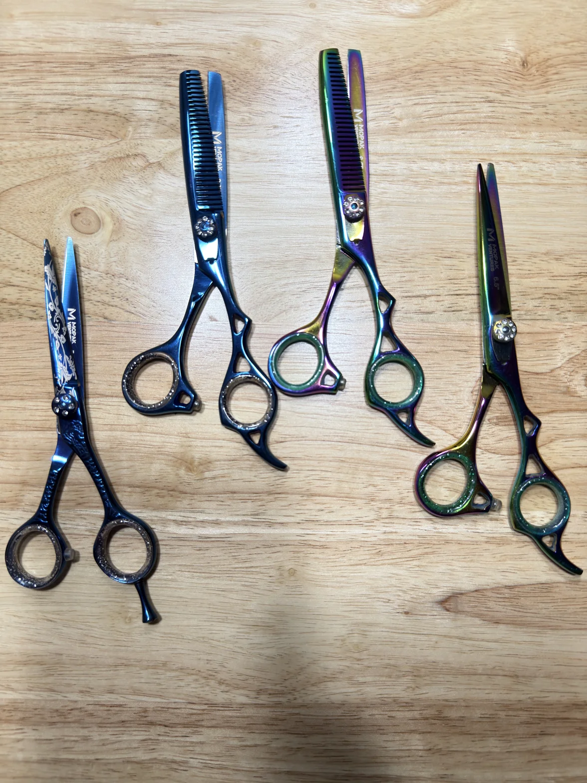 Colorful professional hair-cutting and texturizing scissors arranged on a wooden surface