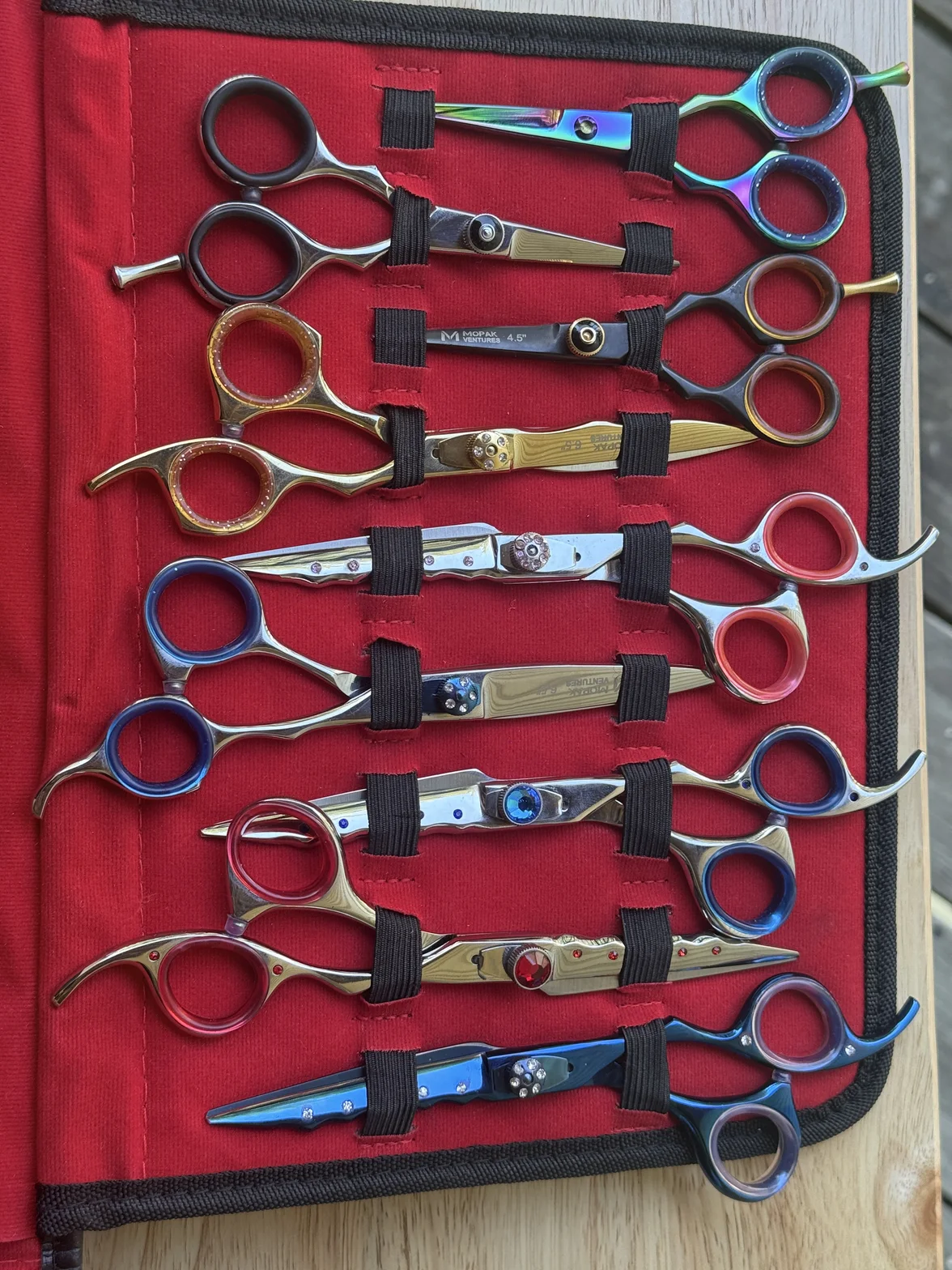 Colorful professional hair-cutting and thinning scissors arranged in a red fabric case with black straps
