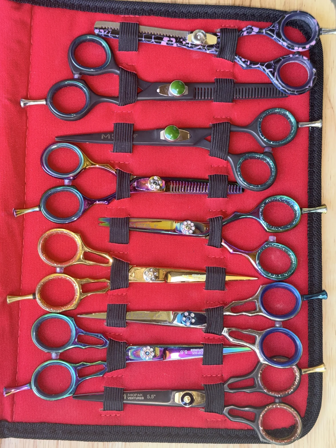 Colorful professional hair-cutting scissors and texturizing shears arranged in a red fabric tool case