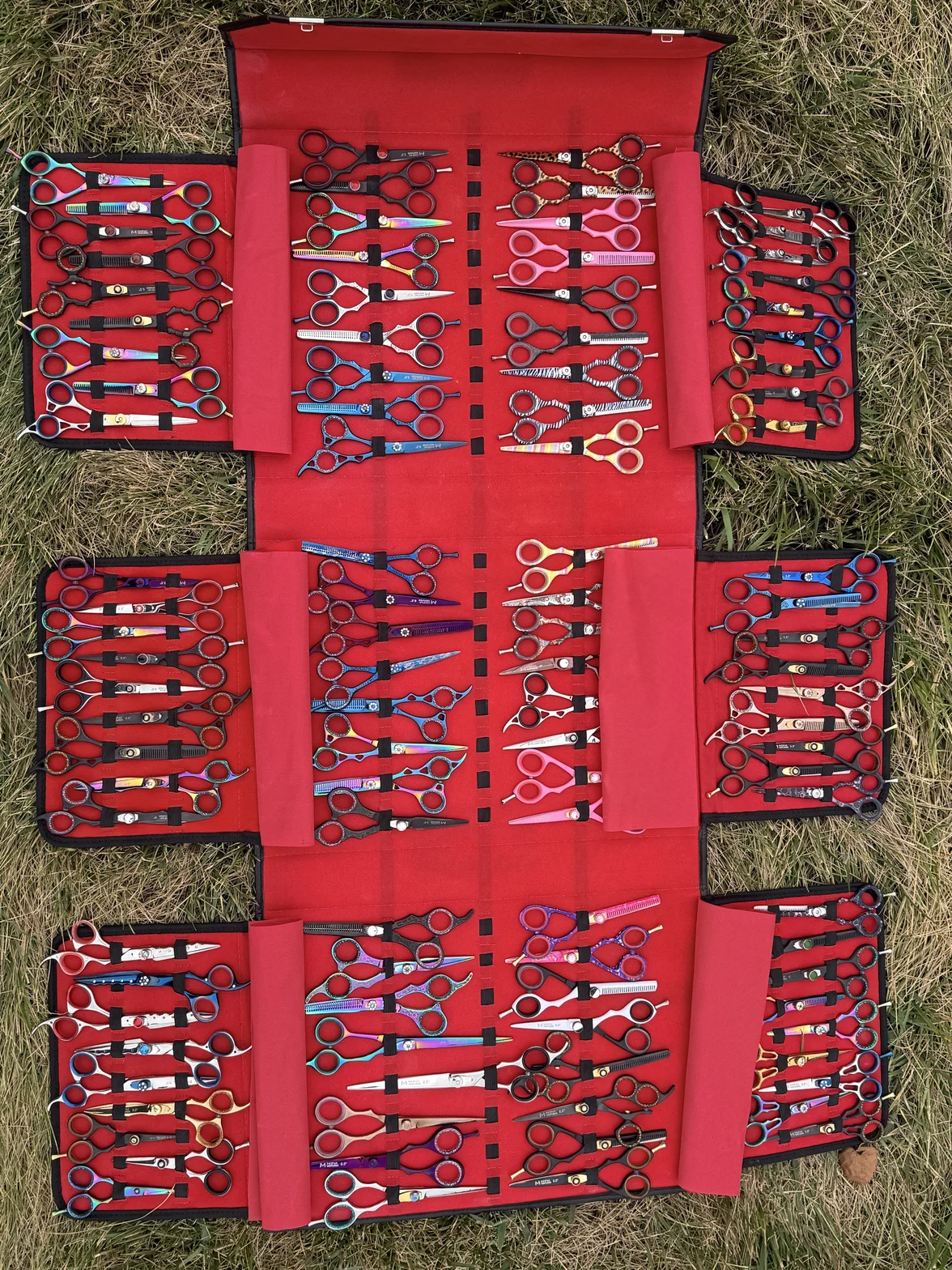 An extensive collection of professional hair shears displayed in red cases, showing dozens of styles, sizes, and handle colors