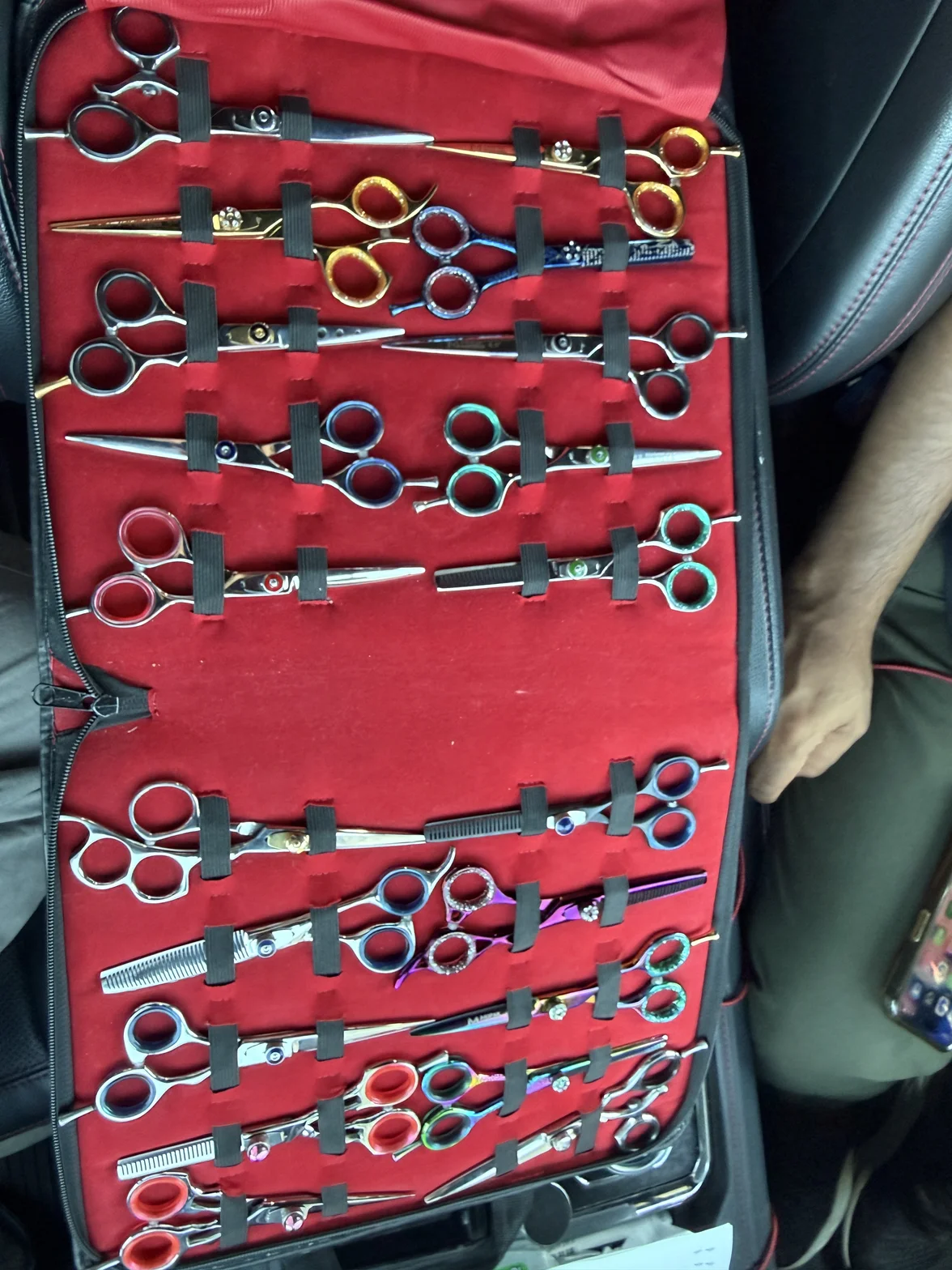 A complete set of handcrafted professional barbering shears organized in a red case with individual compartments and gold and silver handles