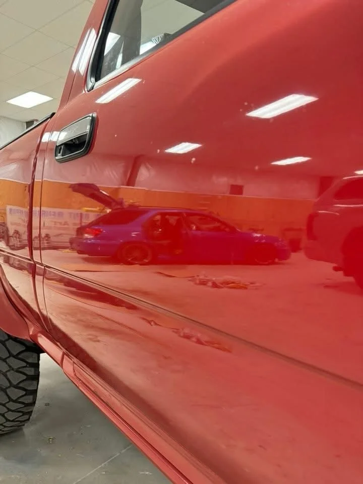High-gloss red custom pickup truck showing deep paint reflections and clean tire finish