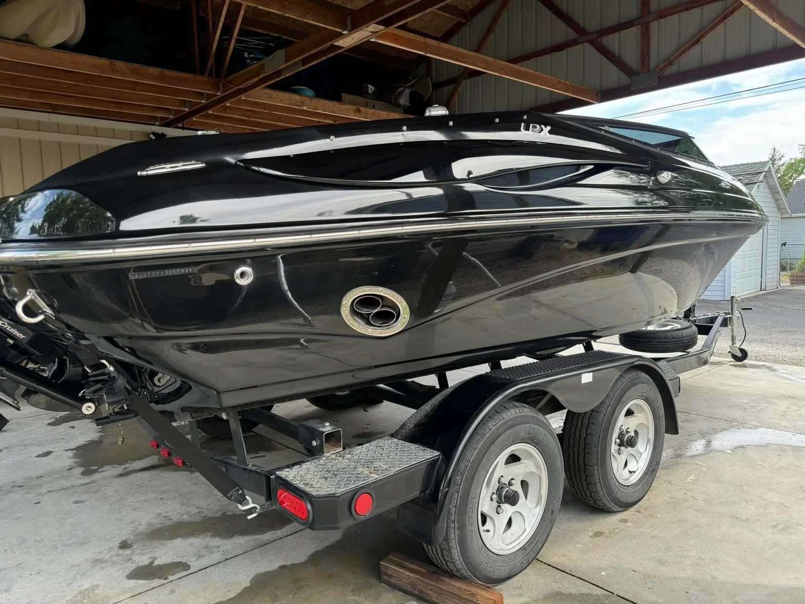 Glossy black recreational boat on trailer with chrome trim and stern drive finish