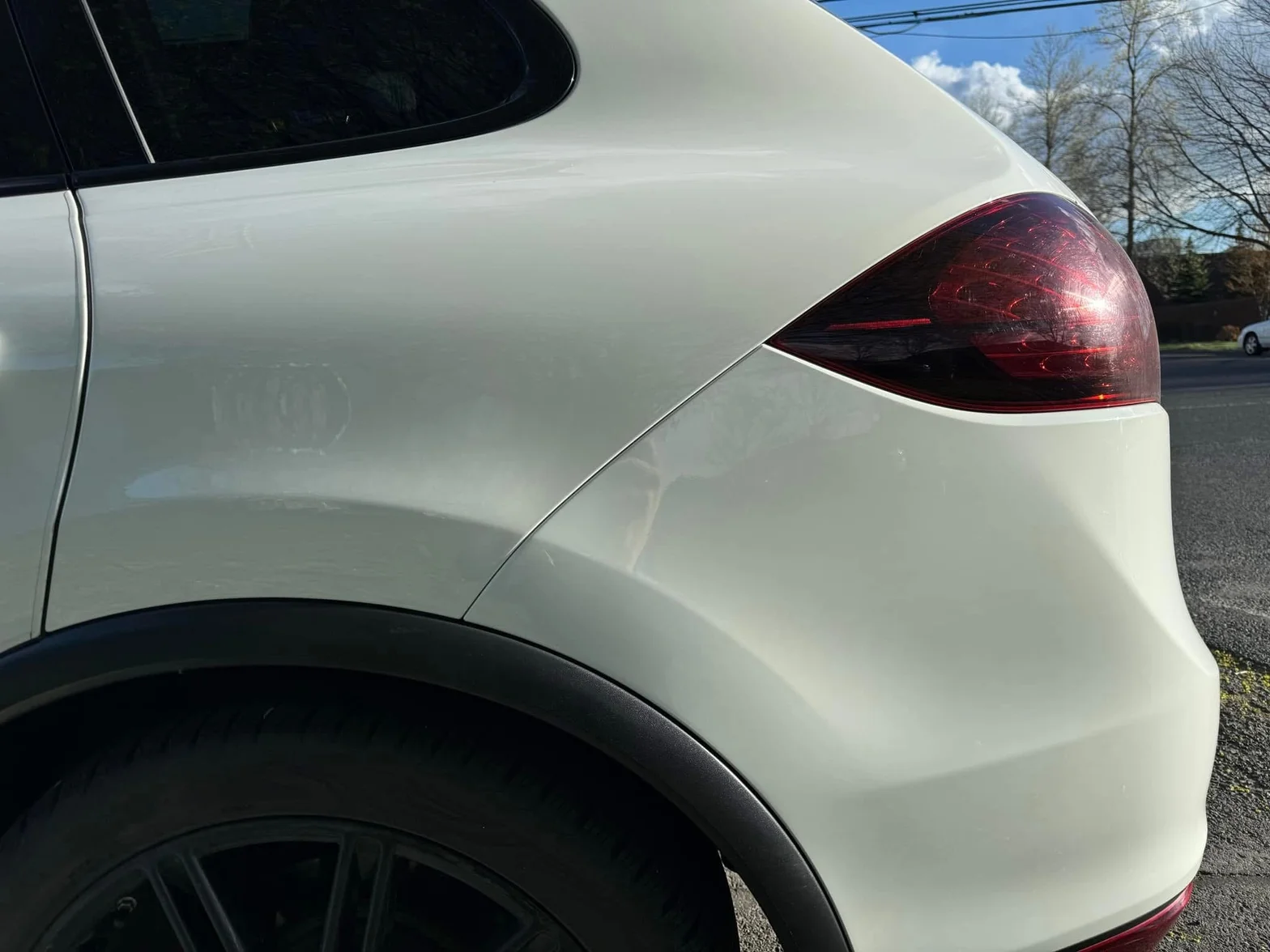 Close-up of a white SUV rear quarter panel and taillight with clean, polished finish
