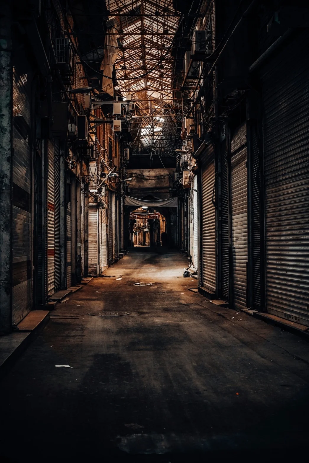 Atmospheric industrial corridor lined with metal shop shutters and exposed brick